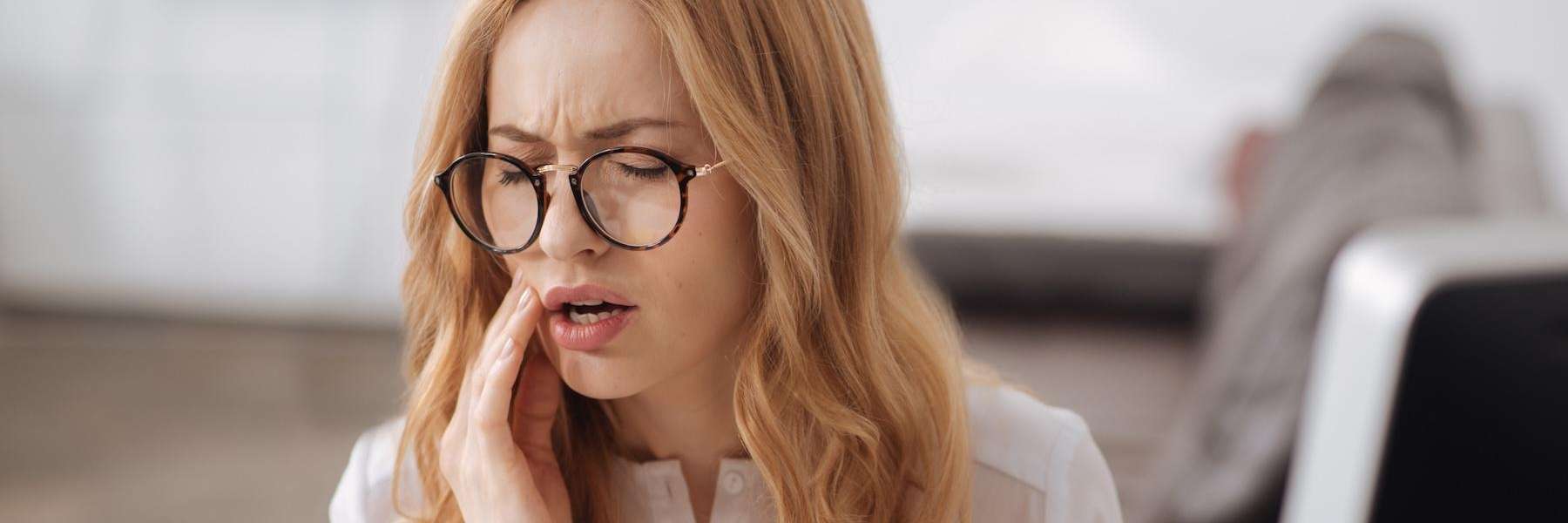 Redhead woman holding her jaw in pain, winston-salem nc