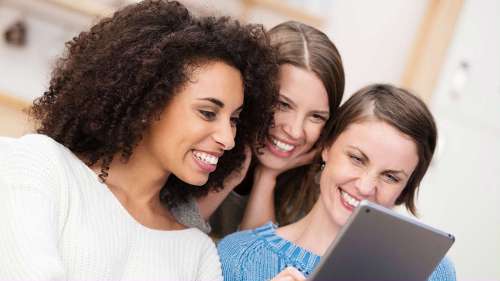 Three women smiling and looking at a tablet, winston-salem nc