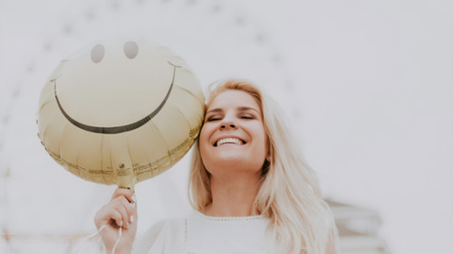 Smiling woman holding a smiley face balloon