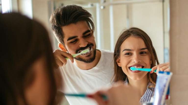 Man and woman brushing their teeth in the mirror, winston-salem nc