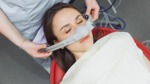 Dental patient receiving nitrous oxide sedation through a nose mask in a dental chair