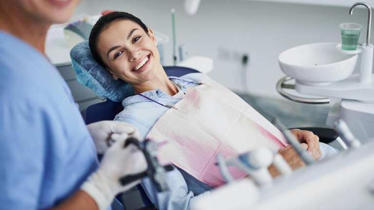 Woman in dental chair smiling after getting a broken dental crown fixed, winston-salem nc