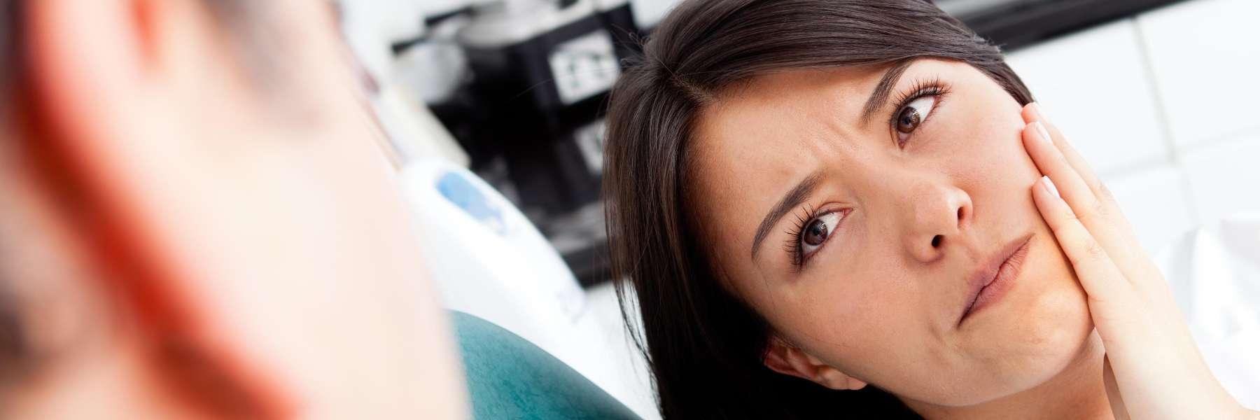 woman in exam chair holding jaw | winston salem dentist